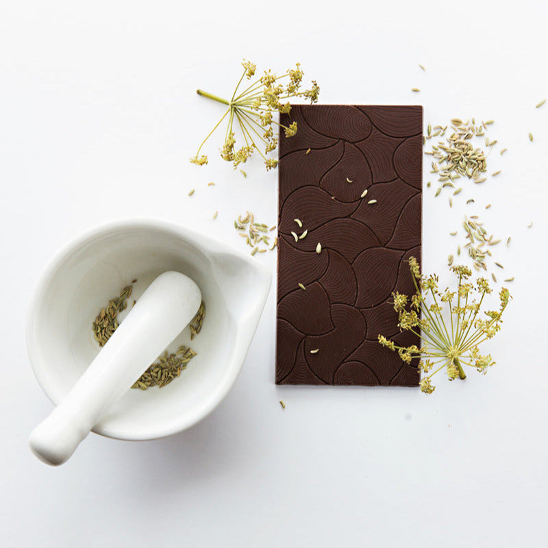 Dark chocolate bar with a white mortar and pestle on a light background