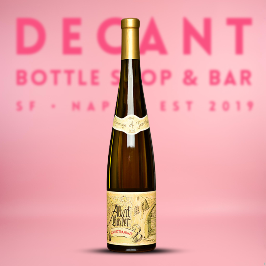 A bottle of Albert Boxler 'Hommage A Jean-Marc' Gewürztraminer wine, with a label featuring artwork and text, set against a pink background.