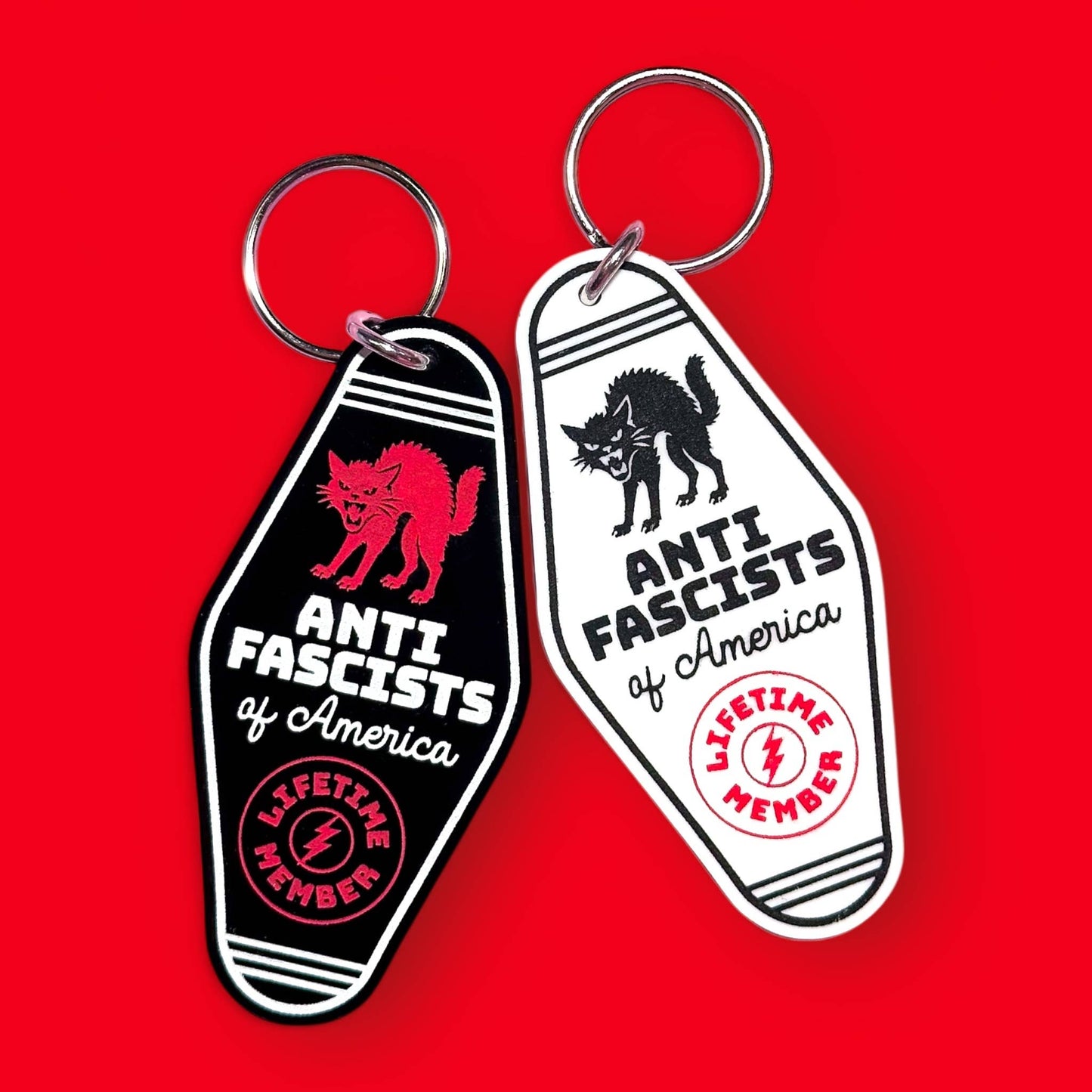 Two keychains with anti-fascist designs on a red background