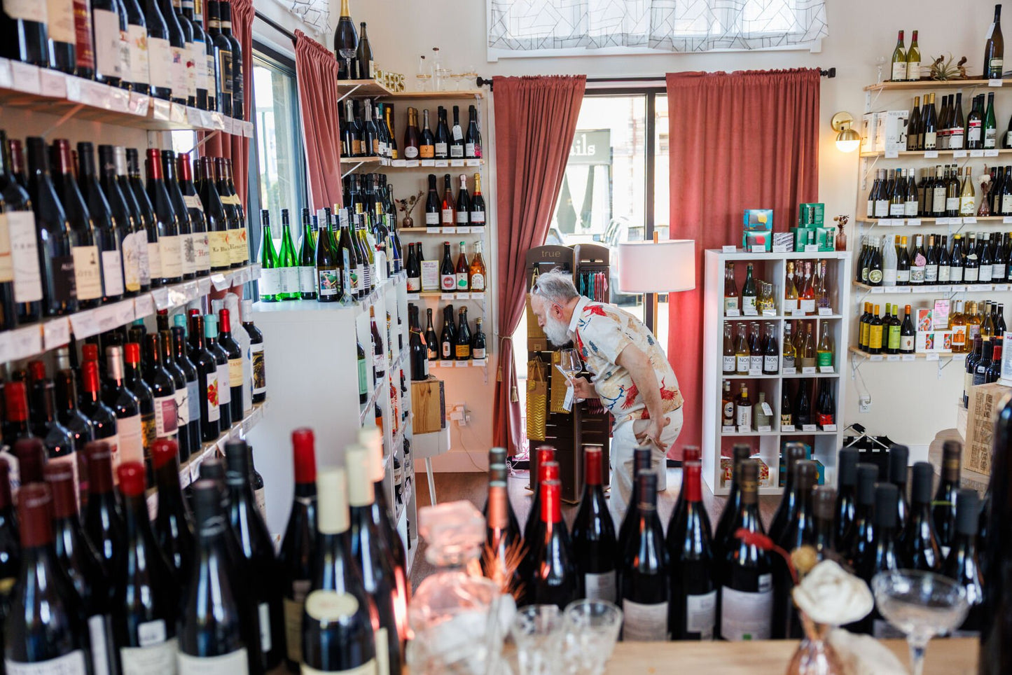 Wine store interior with shelves stocked with bottles and a person browsing.