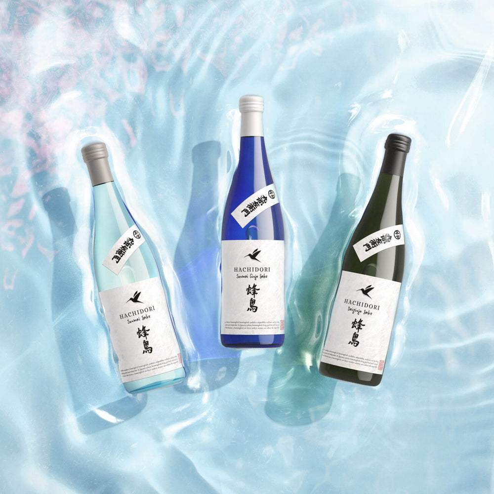 
                  
                    Three bottles of hachidori sake on a water surface with a light blue and pink gradient background
                  
                