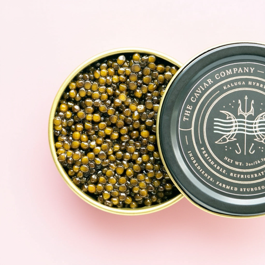 Open tin of Kaluga Hybrid caviar with 'The Caviar Company' branding on a pink background